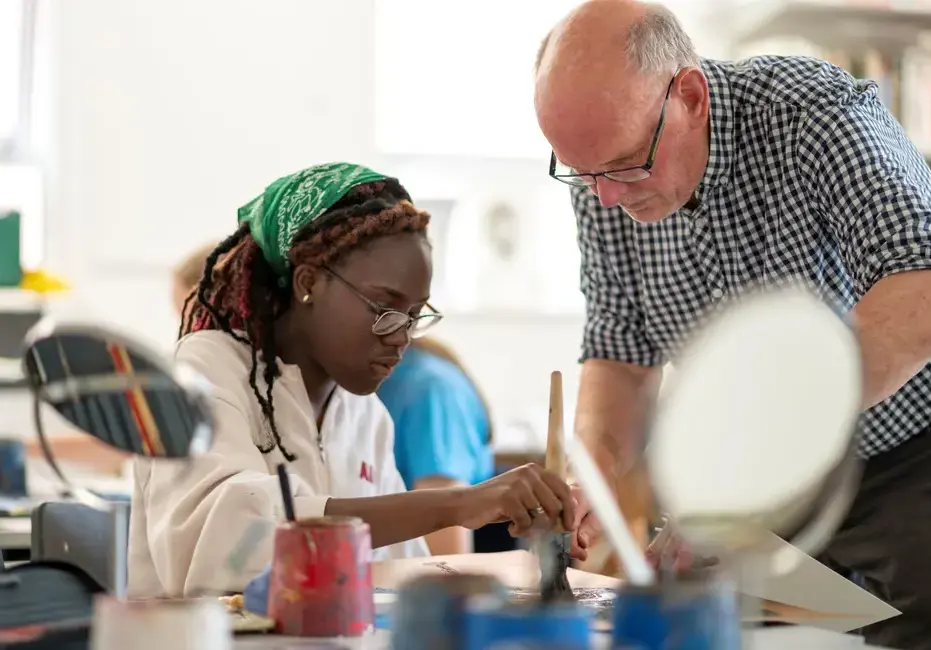 Teacher supervising student during art lesson