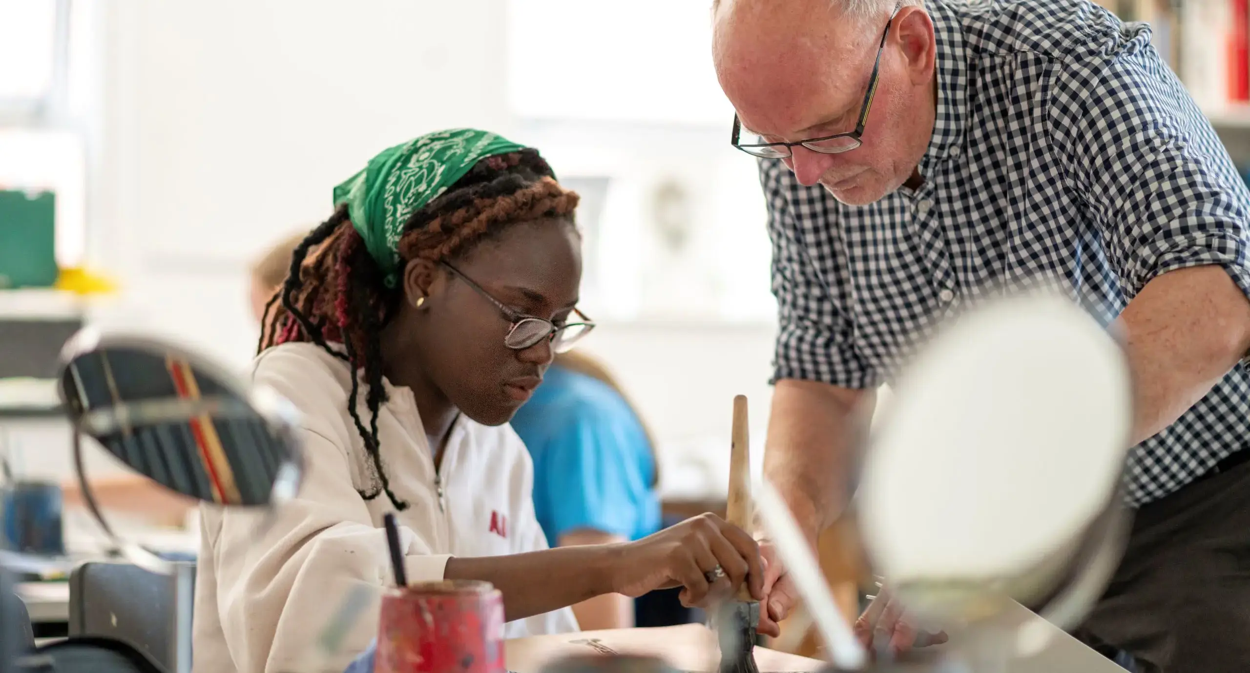 Teacher supervising student during art lesson