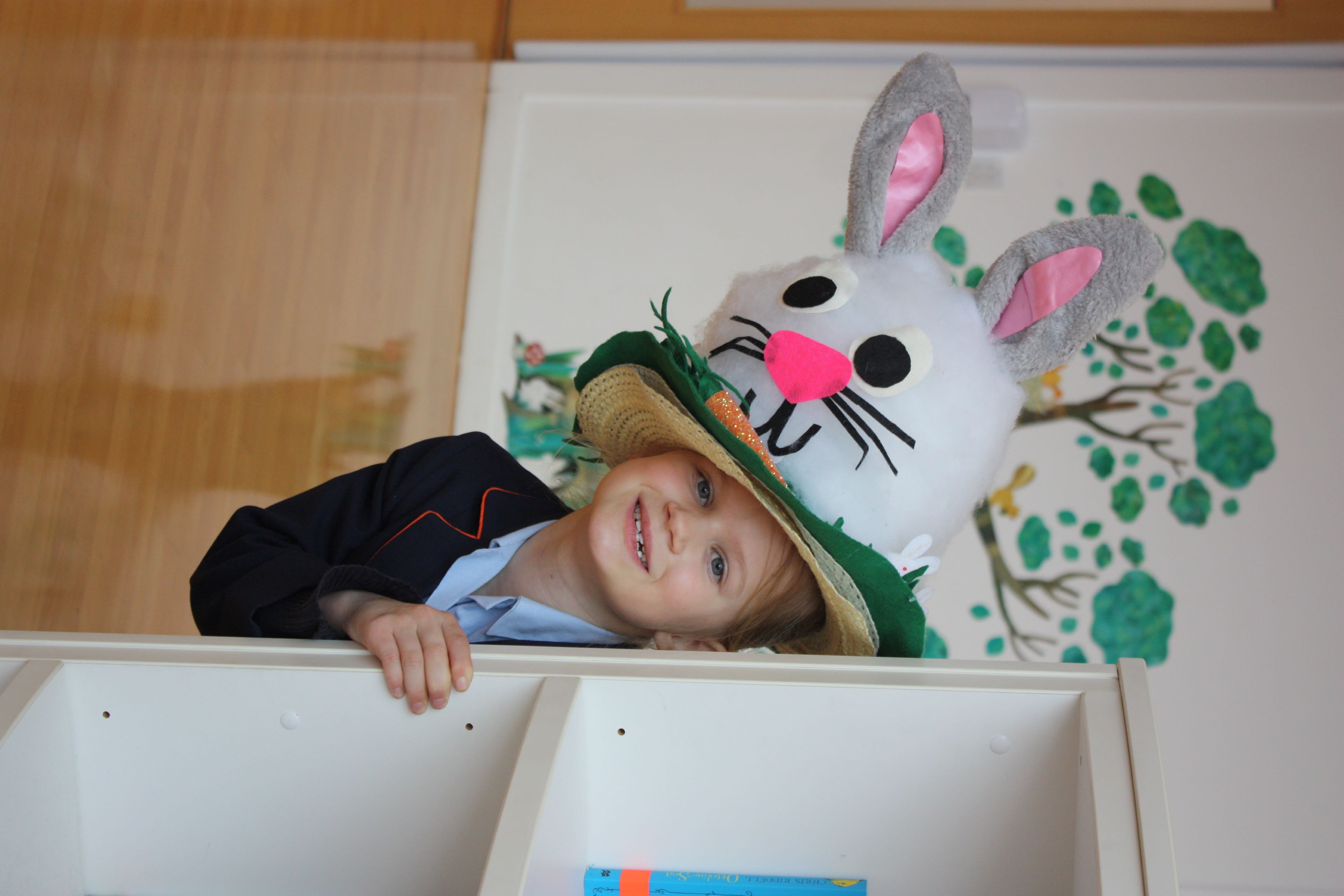 Child in an easter bunny hat hiding behind a bookshelf