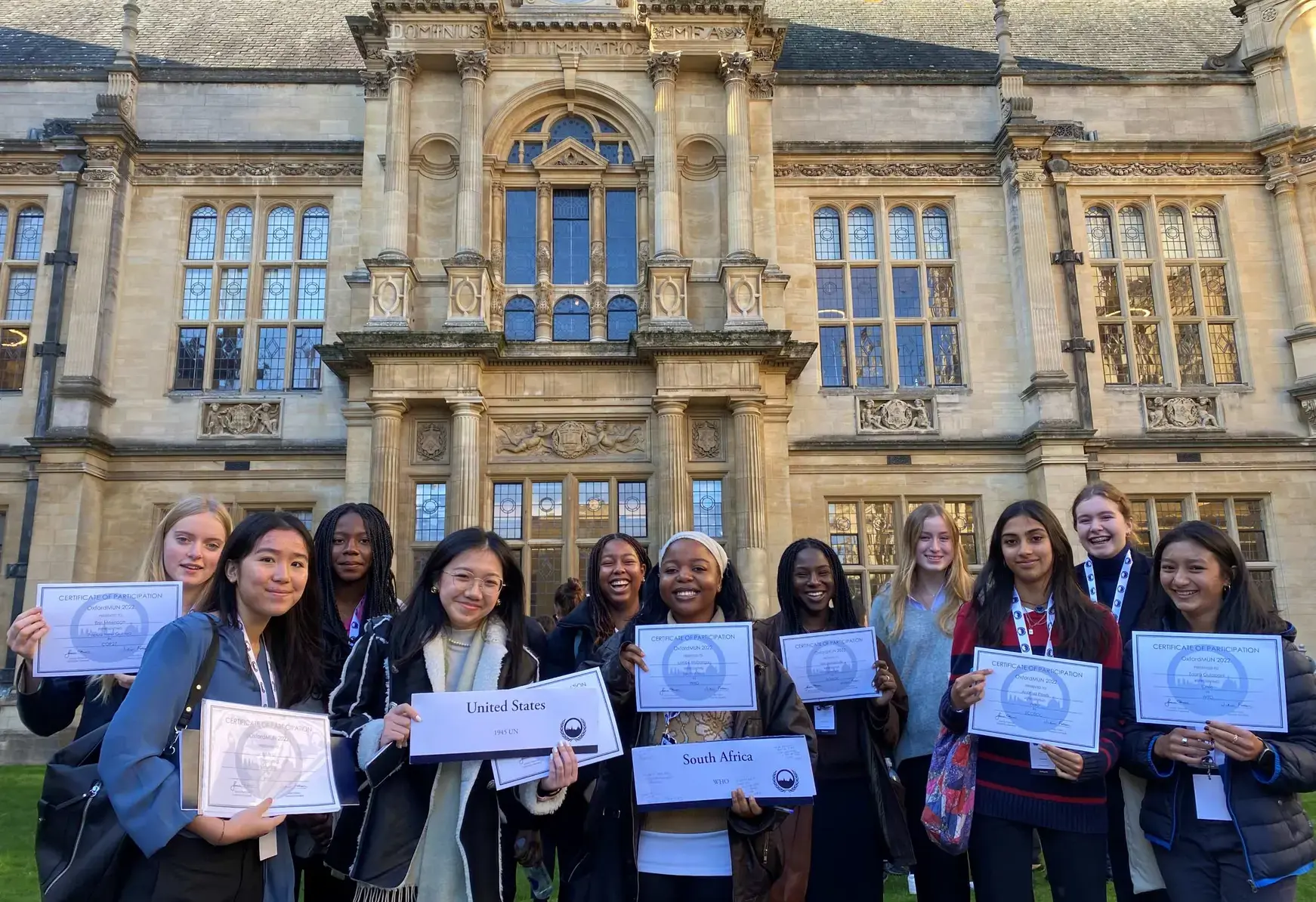 Students outside a building holding certificates