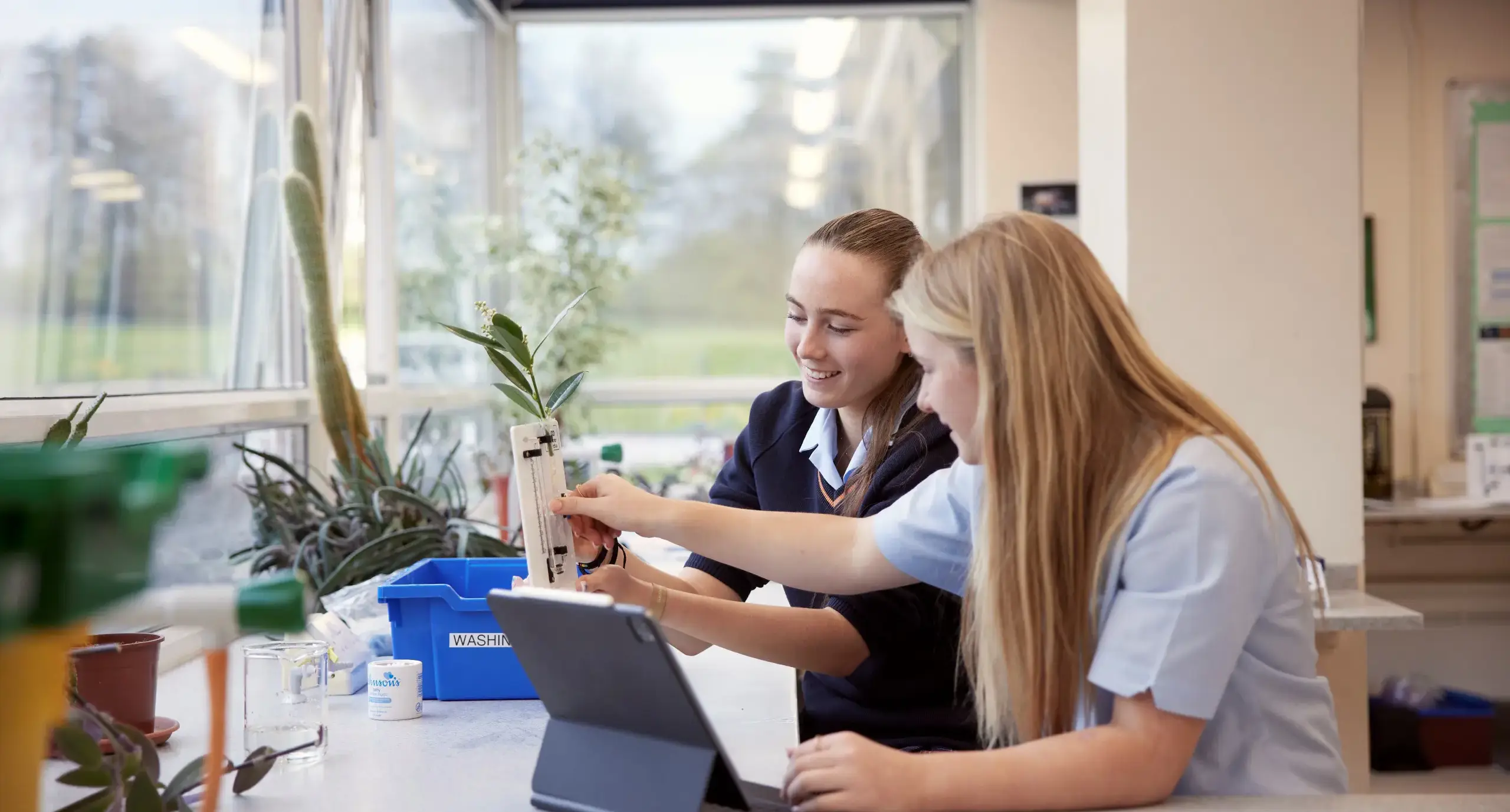 Two students measuring plants in science