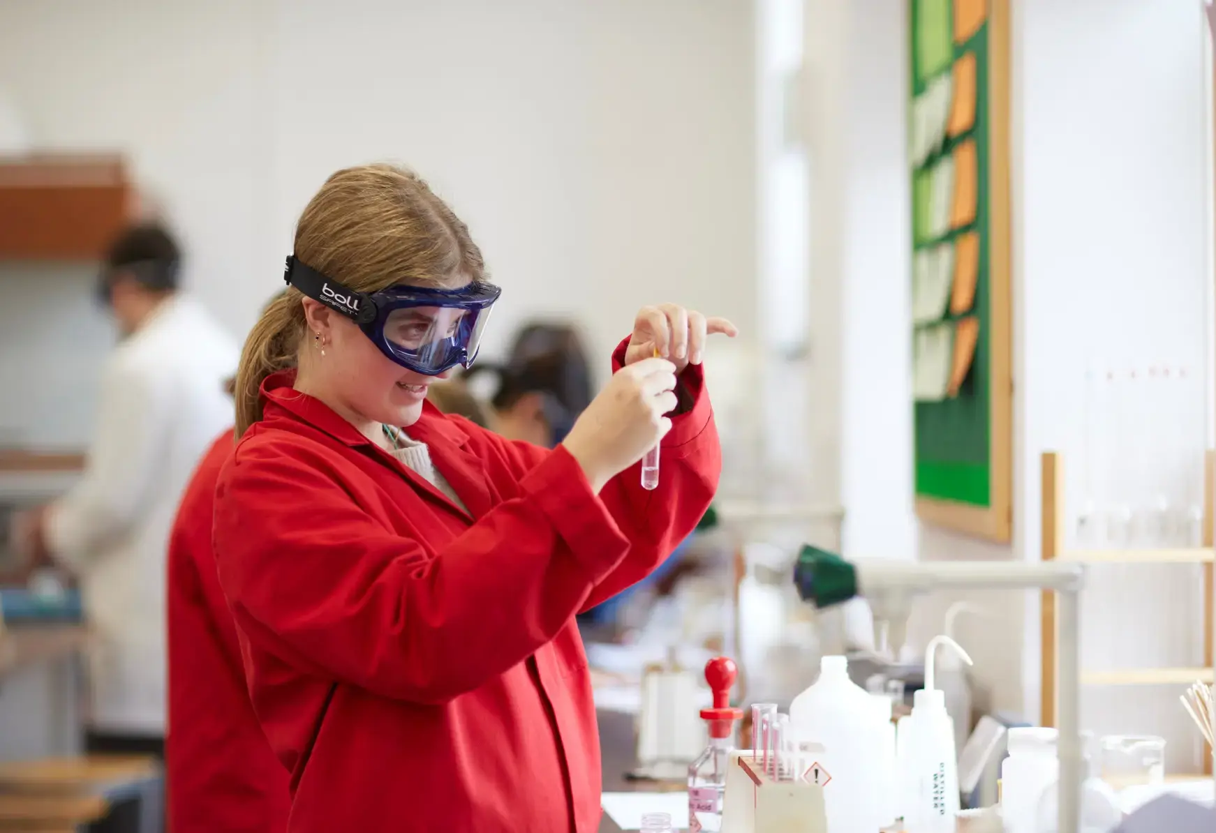 Student in a chemistry lesson, wearing a red lab coat