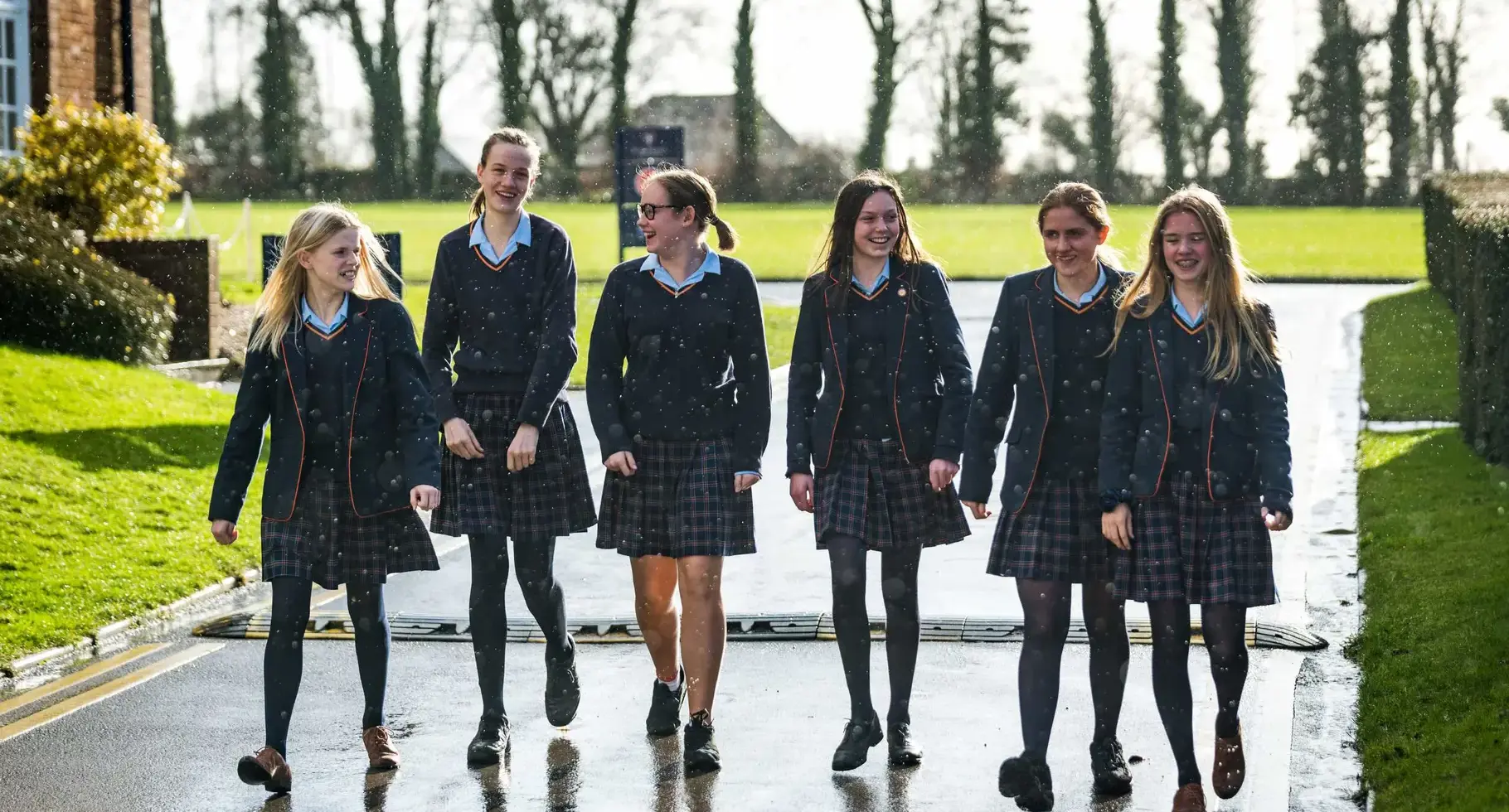 Students walking outside, the pavement shimmering with recent rainfall